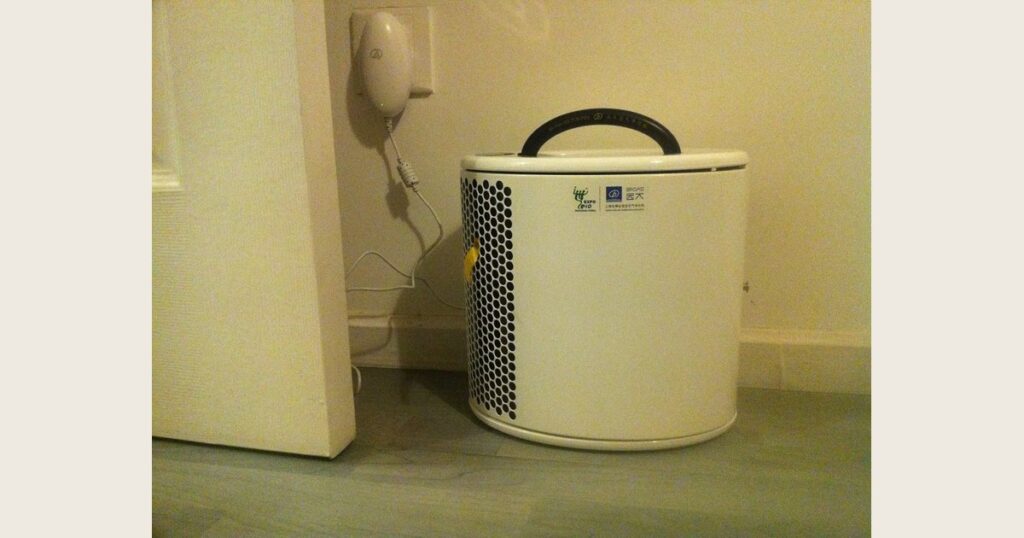 White portable air purifier with a side grille on a hard floor