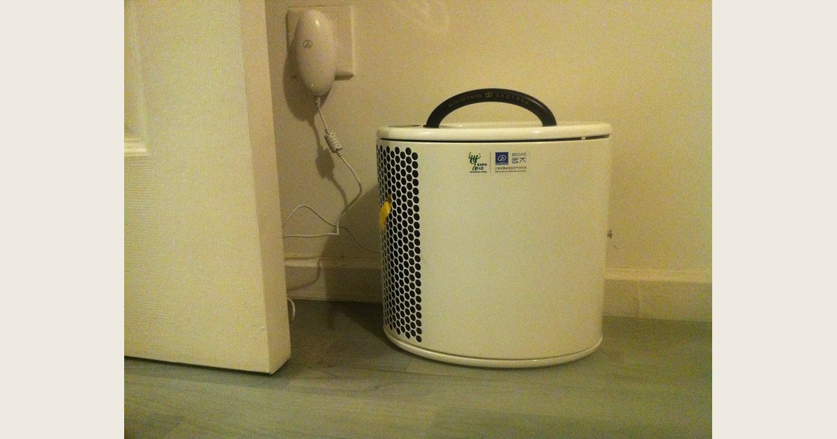 White portable air purifier with a side grille on a hard floor